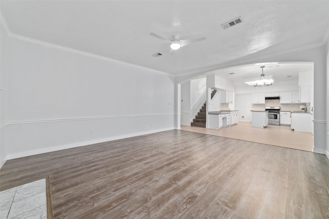 unfurnished living room featuring wood-type flooring and ornamental molding