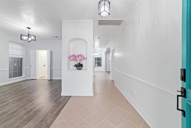 hallway featuring a textured ceiling, a notable chandelier, and light wood-type flooring