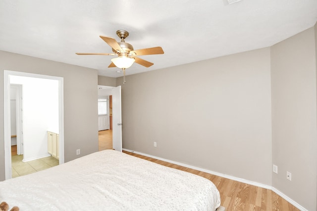 bedroom with ceiling fan, light wood-type flooring, and connected bathroom