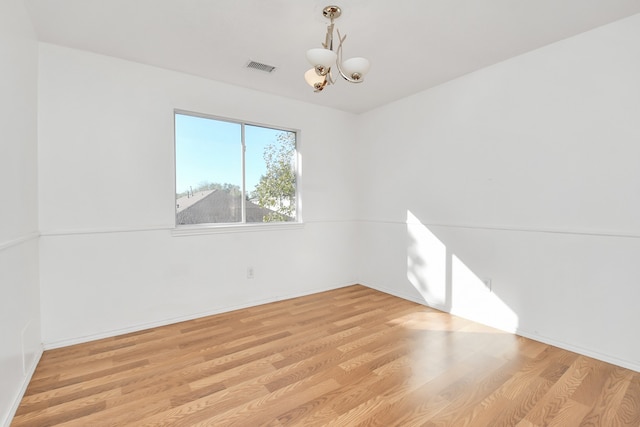 unfurnished room with an inviting chandelier and light hardwood / wood-style flooring