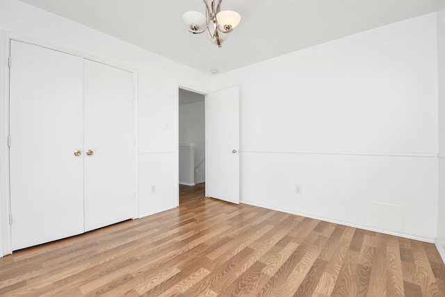 unfurnished bedroom featuring light hardwood / wood-style floors, an inviting chandelier, and a closet