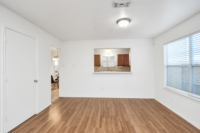 unfurnished living room featuring hardwood / wood-style floors, an inviting chandelier, and sink