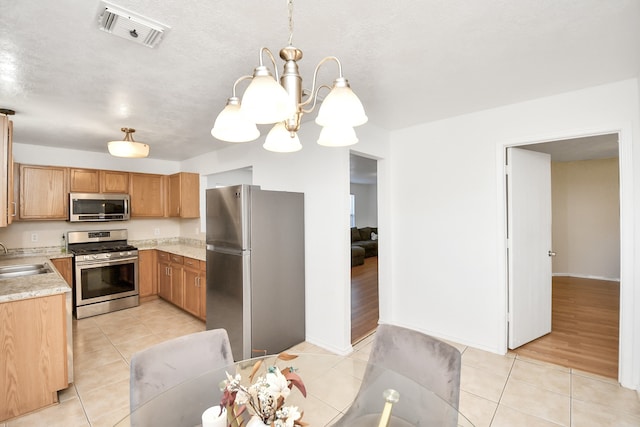 kitchen with sink, hanging light fixtures, light hardwood / wood-style floors, a chandelier, and appliances with stainless steel finishes