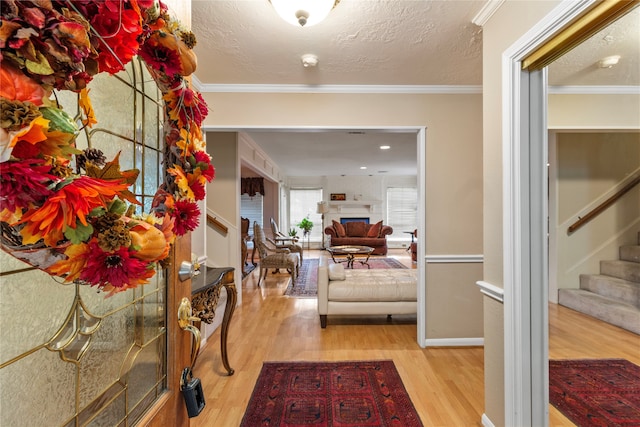 corridor featuring a textured ceiling, light wood-type flooring, and ornamental molding