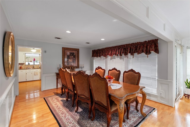 dining area with light wood-type flooring and ornamental molding