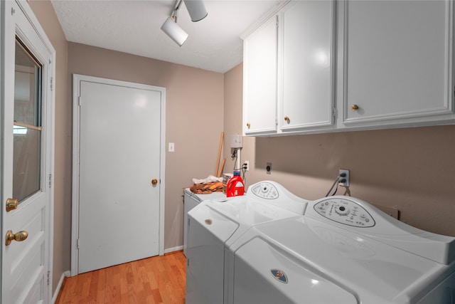 laundry room with cabinets, light wood-type flooring, track lighting, a textured ceiling, and washing machine and clothes dryer