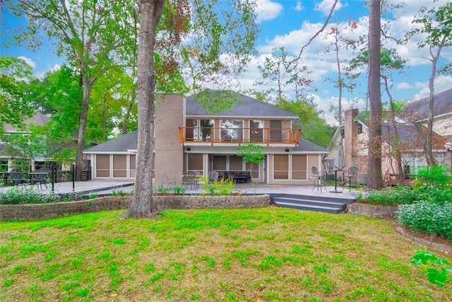 back of house featuring a lawn, a sunroom, a balcony, and a patio