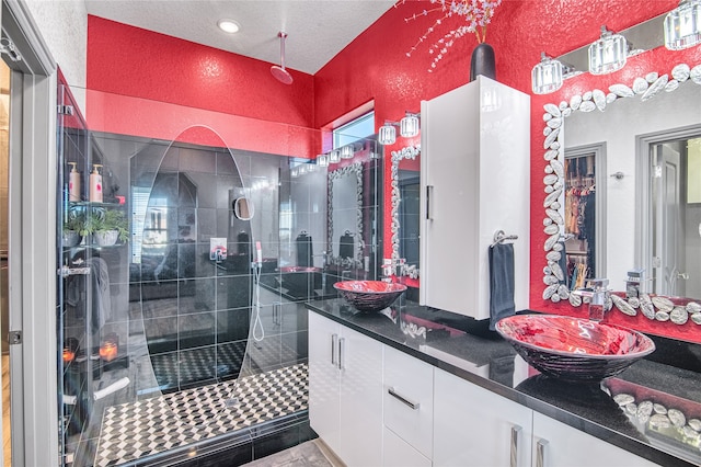 bathroom with a textured ceiling, vanity, and a shower with door