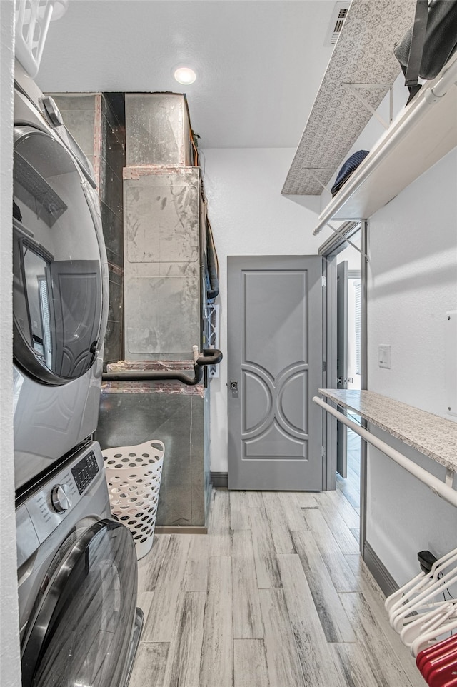 washroom with light wood-type flooring and stacked washer and clothes dryer