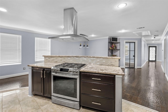 kitchen with dark brown cabinetry, stainless steel gas range oven, light hardwood / wood-style flooring, crown molding, and island range hood