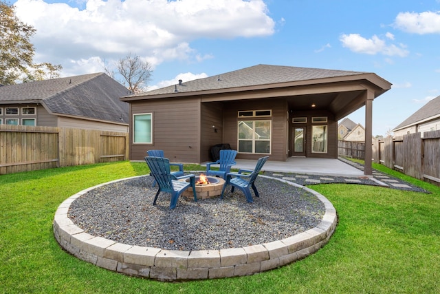 back of property with a fire pit, a yard, and a patio