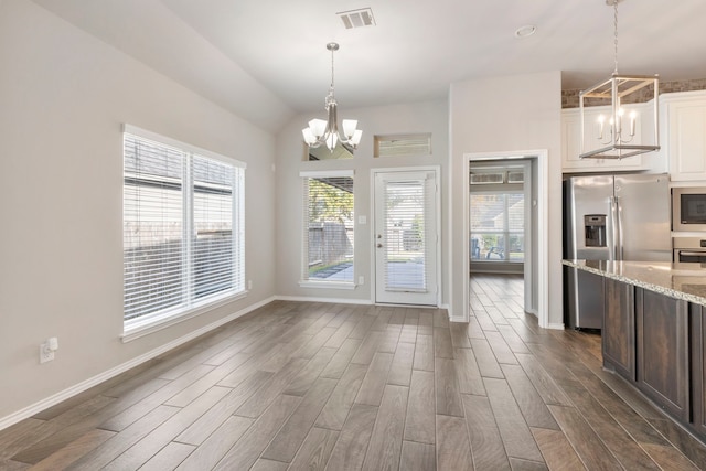 unfurnished dining area featuring dark hardwood / wood-style floors, an inviting chandelier, plenty of natural light, and lofted ceiling