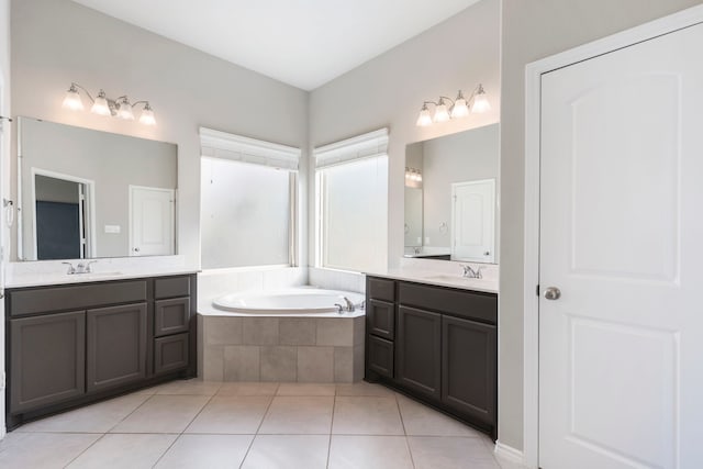 bathroom with tile patterned floors, tiled bath, and vanity