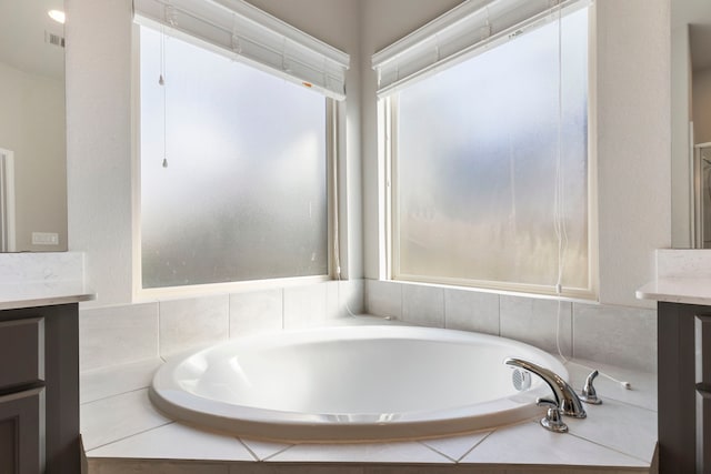 bathroom featuring vanity and tiled tub