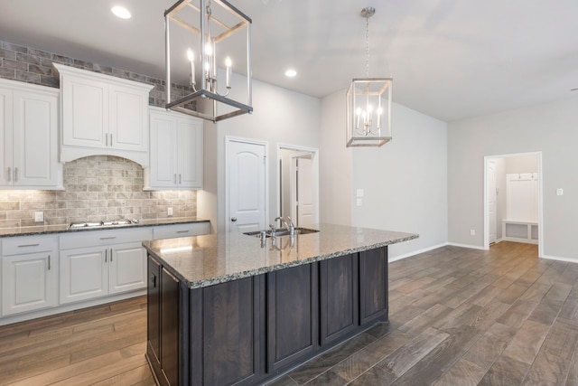 kitchen with pendant lighting, dark hardwood / wood-style floors, white cabinetry, and an island with sink