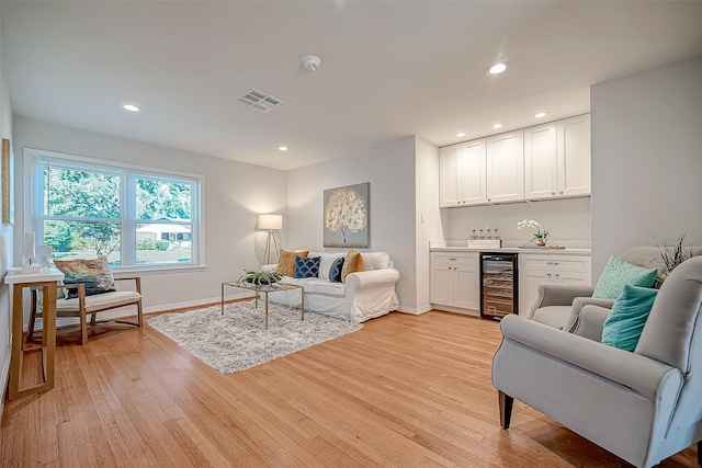 living room featuring bar area, beverage cooler, and light hardwood / wood-style floors