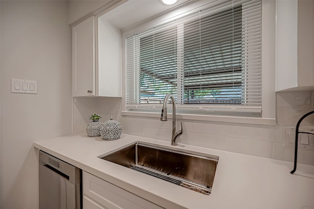 kitchen featuring sink, white cabinets, stainless steel dishwasher, and backsplash