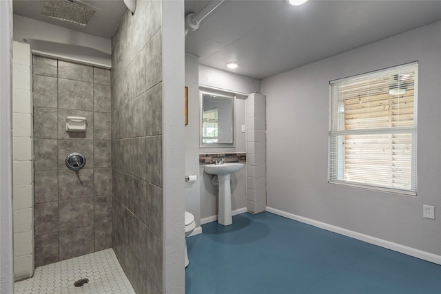 bathroom with tiled shower, concrete flooring, toilet, and plenty of natural light