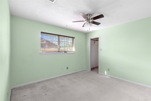 spare room featuring a textured ceiling, light colored carpet, and ceiling fan