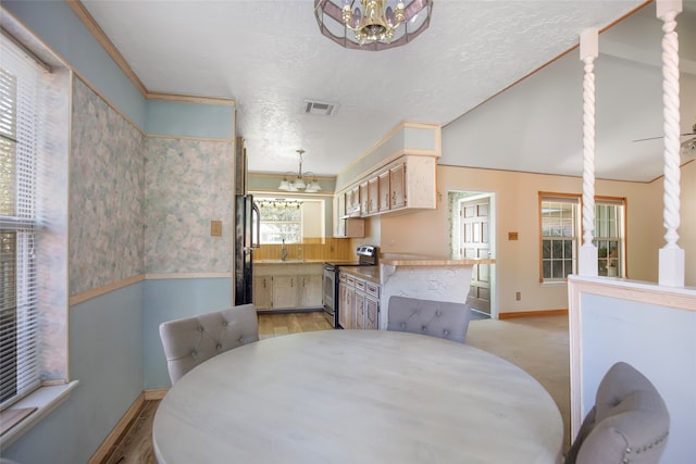 dining room featuring a textured ceiling, light wood-type flooring, sink, and an inviting chandelier