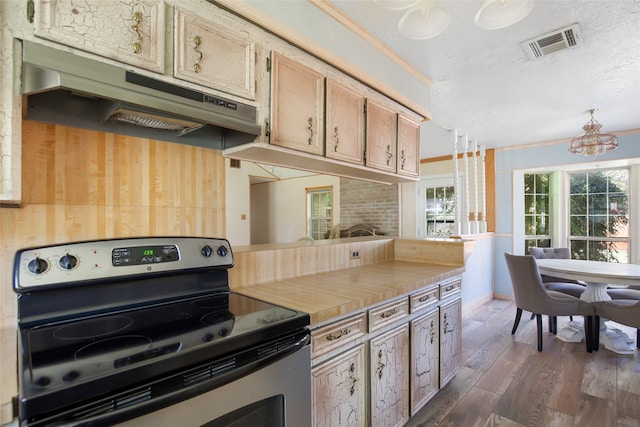 kitchen with light brown cabinetry, dark hardwood / wood-style flooring, ornamental molding, electric stove, and decorative light fixtures