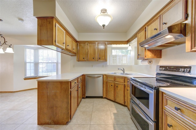 kitchen featuring a wealth of natural light, sink, stainless steel appliances, kitchen peninsula, and decorative light fixtures