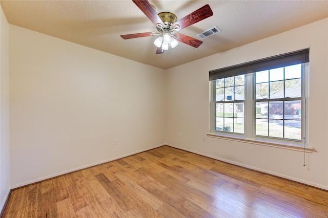 empty room featuring ceiling fan, light hardwood / wood-style floors, and a textured ceiling