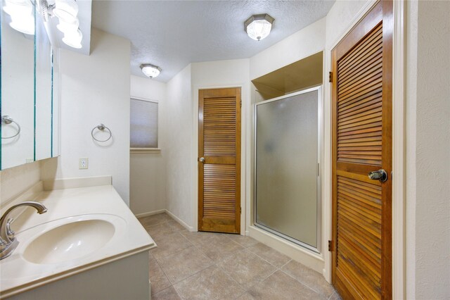 bathroom with vanity, a shower with door, and a textured ceiling