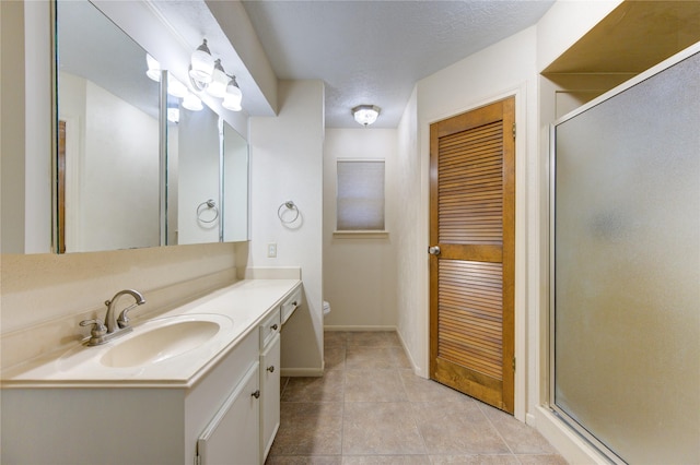 bathroom featuring tile patterned flooring, vanity, a textured ceiling, and walk in shower