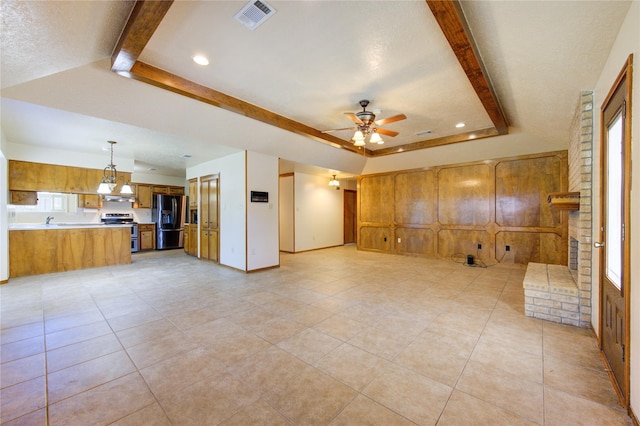 unfurnished living room with plenty of natural light, ceiling fan, a raised ceiling, and a textured ceiling