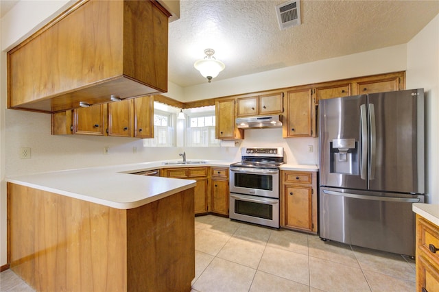 kitchen featuring sink, kitchen peninsula, a textured ceiling, light tile patterned flooring, and appliances with stainless steel finishes