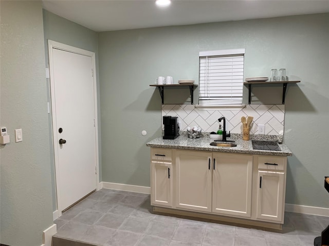 kitchen with light stone countertops, tasteful backsplash, and sink