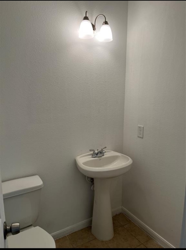 bathroom featuring toilet, tile patterned floors, and sink