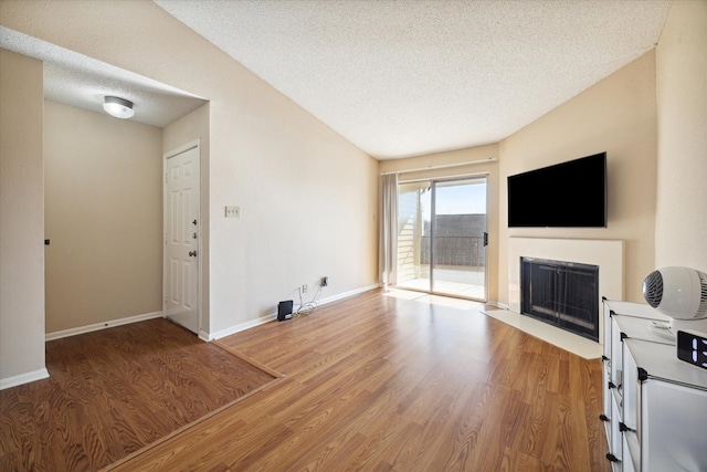 living room with hardwood / wood-style floors, a textured ceiling, and vaulted ceiling