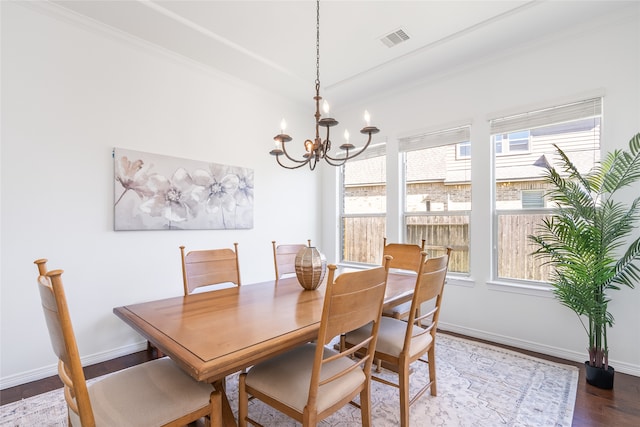 dining space featuring hardwood / wood-style floors, an inviting chandelier, and crown molding