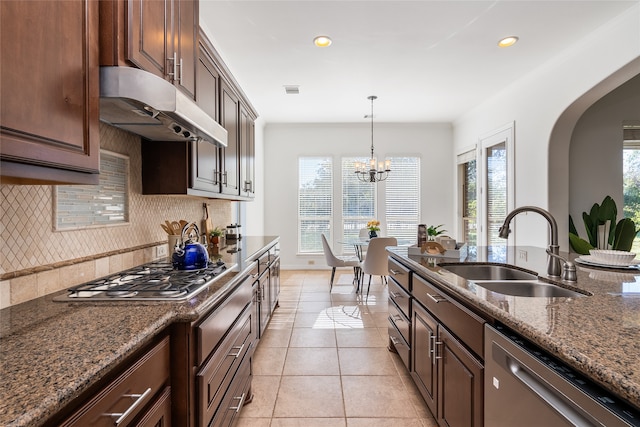 kitchen with sink, a notable chandelier, stone countertops, dark brown cabinets, and appliances with stainless steel finishes