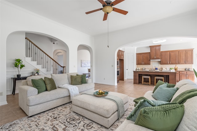 tiled living room with crown molding, sink, and ceiling fan