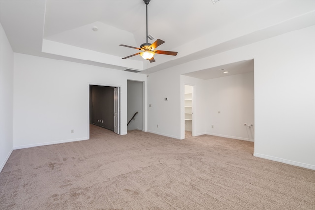 carpeted empty room with a raised ceiling and ceiling fan