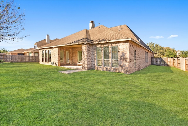 rear view of house featuring a yard and a patio