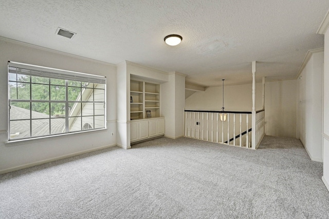 unfurnished room with carpet, a textured ceiling, and crown molding