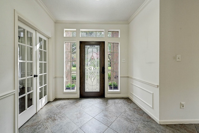 foyer entrance featuring crown molding, a textured ceiling, and french doors