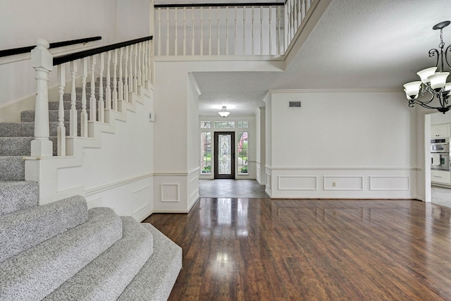 foyer entrance with a chandelier, a textured ceiling, dark hardwood / wood-style flooring, and ornamental molding