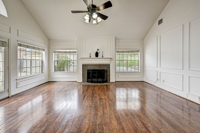 unfurnished living room featuring a tiled fireplace, ceiling fan, a healthy amount of sunlight, and hardwood / wood-style flooring