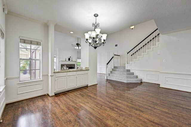 interior space featuring ceiling fan with notable chandelier, crown molding, decorative light fixtures, white cabinets, and dark hardwood / wood-style floors