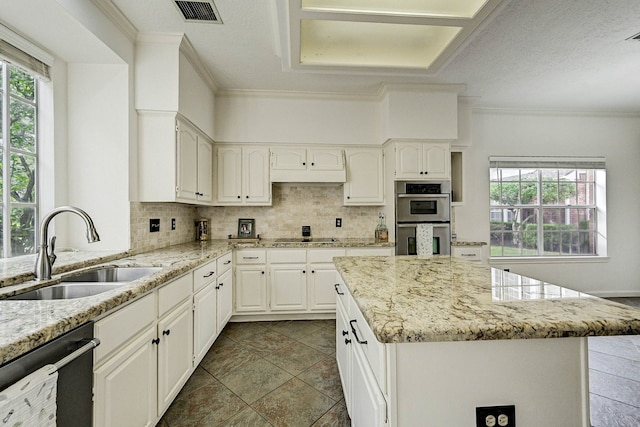 kitchen with appliances with stainless steel finishes, backsplash, light stone counters, sink, and white cabinetry