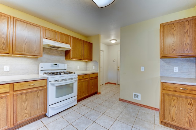 kitchen with decorative backsplash, light tile patterned flooring, and white gas range oven