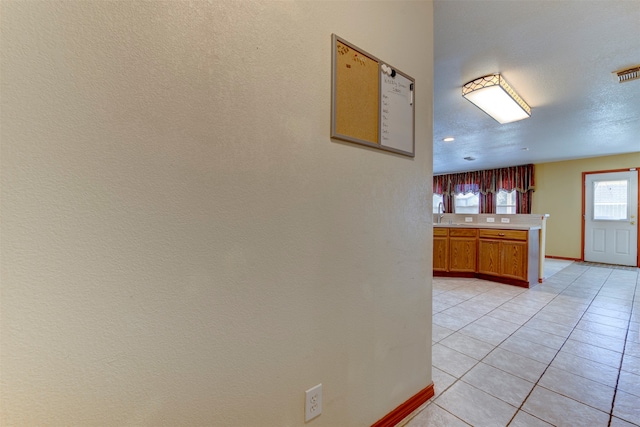 corridor featuring a textured ceiling and light tile patterned flooring