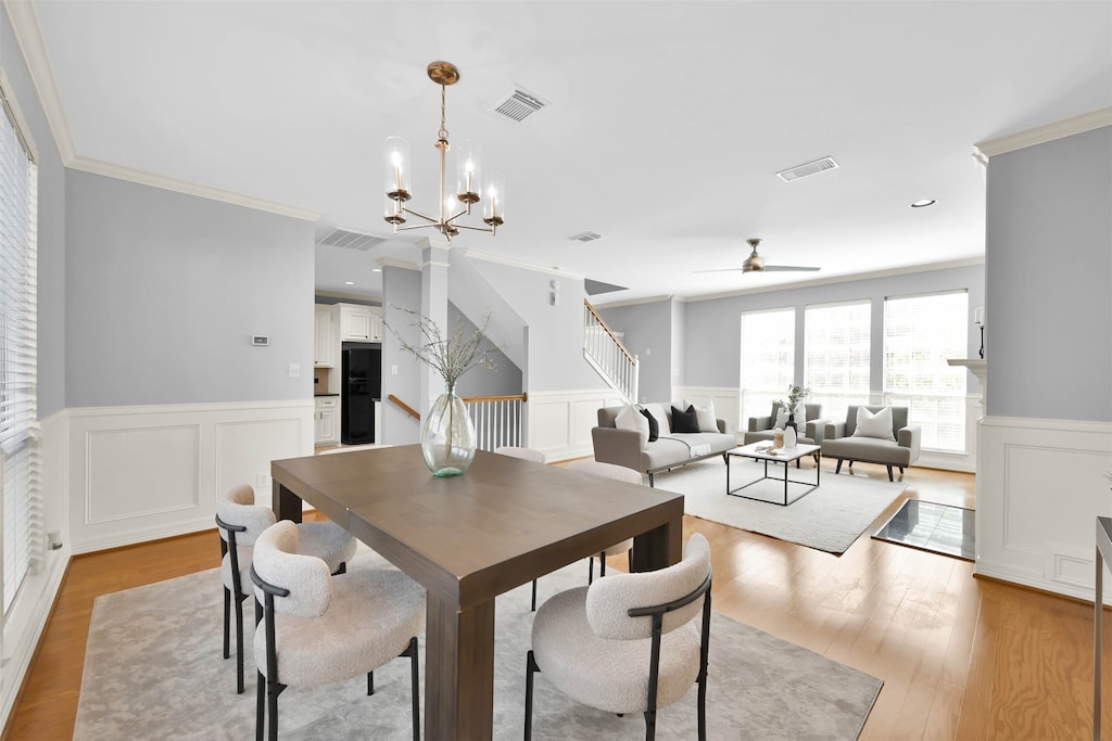 dining space featuring light hardwood / wood-style flooring, ceiling fan with notable chandelier, and ornamental molding