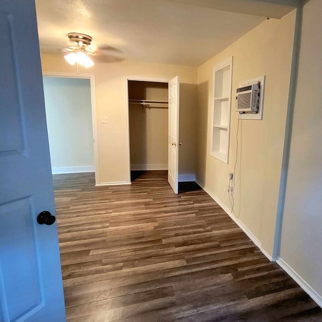 unfurnished bedroom with a wall mounted air conditioner, dark hardwood / wood-style flooring, a closet, and ceiling fan