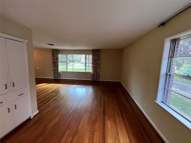 unfurnished room with dark wood-type flooring